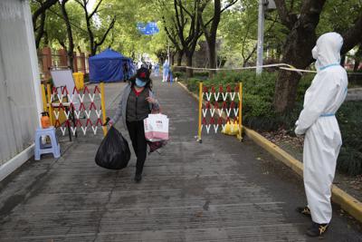 Fotografía proporcionada por la agencia de noticias Xinhua de una persona regresando a casa después de estar en cuarentena por casos de COVID-19 detectados en la aldea Lianqin de Beicai Town en Pudong New Area, Shanghái, el martes 26 de abril de 2022. (Jin Liwang/Xinhua vía AP)