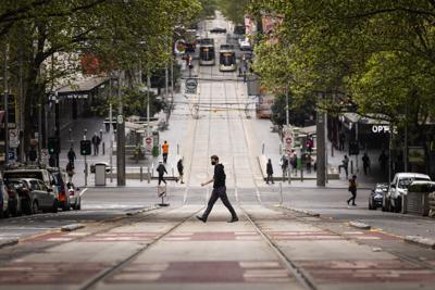 Gente cruzando la calle Bourke en Melbourne, el jueves 30 de septiembre de 2021. El estado australiano de Victoria reportó un aumento de más del 50% en los contagios diarios de COVID-19, que las autoridades atribuyeron en gran parte a fiestas relacionadas con el fútbol australiano, celebradas el fin de semana pasado y que incumplieron las normas de distanciamiento social. (Daniel Pockett/AAP Image via AP)