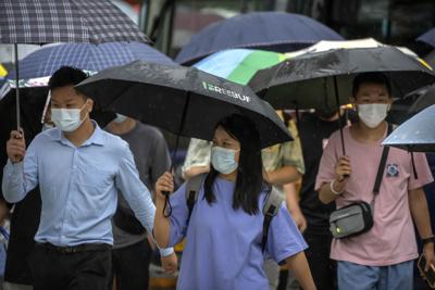 Personas con cubrebocas caminan por una calle del distrito comercial de Beijing, el 9 de agosto de 2022. (AP Foto/Mark Schiefelbein)