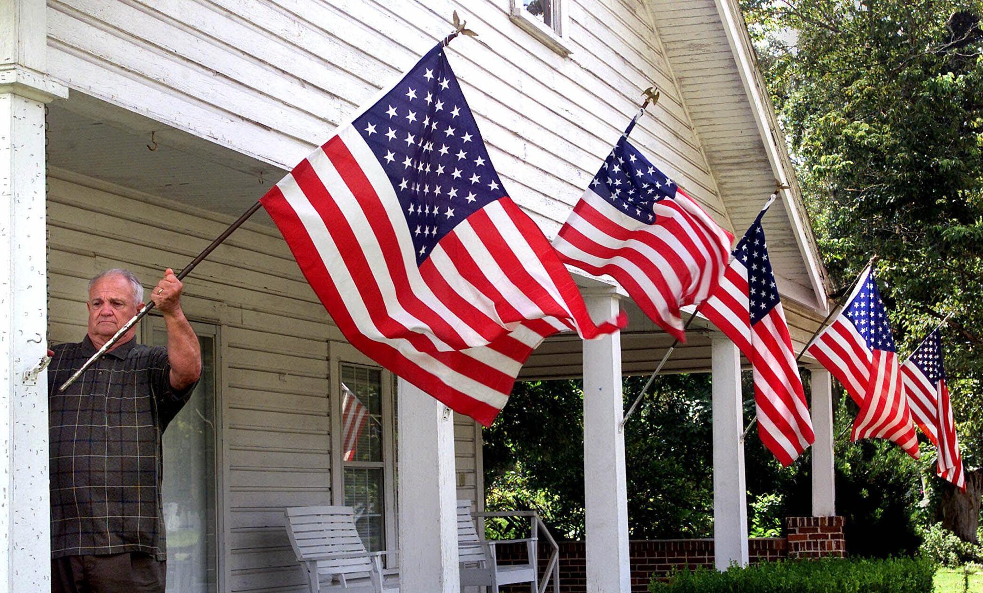 FILE - In this Thursday, Sept. 13, 2001 file photo, Liberty County resident Rev. M. Timonthy Elder, Sr., retired, repositions one of his wind-blown U.S. flags in Bristol, Fla. Rev. Elder displayed the flags as a show of his family's support for America following terrorist attacks in New York City and Washington two days earlier. (AP Photo/Phil Coale, File)