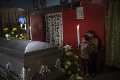 Dos de seis hijos del periodista Julio Valdivia están junto al ataúd de su padre, en su velorio en su casa en Tezonapa, Veracruz, México, el 10 de septiembre de 2020. El cadáver decapitado de Valdivia fue hallado un día antes. Los homicidios en México no bajaron a pesar de la pandemia, de acuerdo con un informe publicado el 27 de julio de 2021. (AP Foto/Felix Marquez, File)