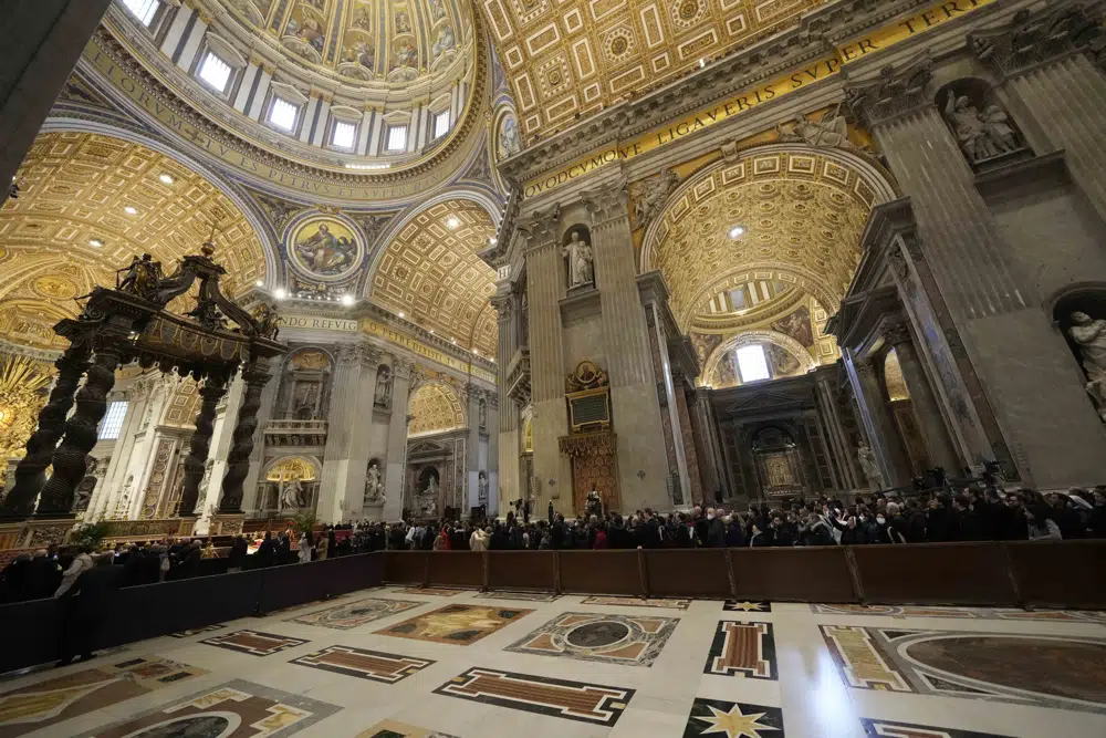 People look at the body of late Pope Emeritus Benedict XVI laid out in state inside St. Peter's Basilica at The Vatican, Monday, Jan. 2, 2023. Benedict XVI, the German theologian who will be remembered as the first pope in 600 years to resign, has died, the Vatican announced Saturday. He was 95. (AP Photo/Andrew Medichini)