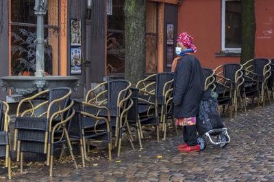 Una mujer pasa por una terraza vacía en el barrio de Marrolles en Bruselas, Bélgica, el 17 de noviembre de 2021. (Foto AP/Olivier Matthys, archivo)