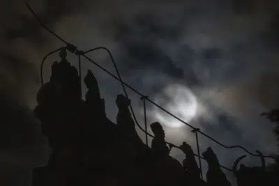 Las decoraciones del techo que representan bestias sagradas míticas se recortan cerca de un eclipse lunar penumbral parcialmente bloqueado por las nubes durante las primeras horas del sábado 6 de mayo de 2023 en Beijing. (AP Photo/Ng Han Guan)