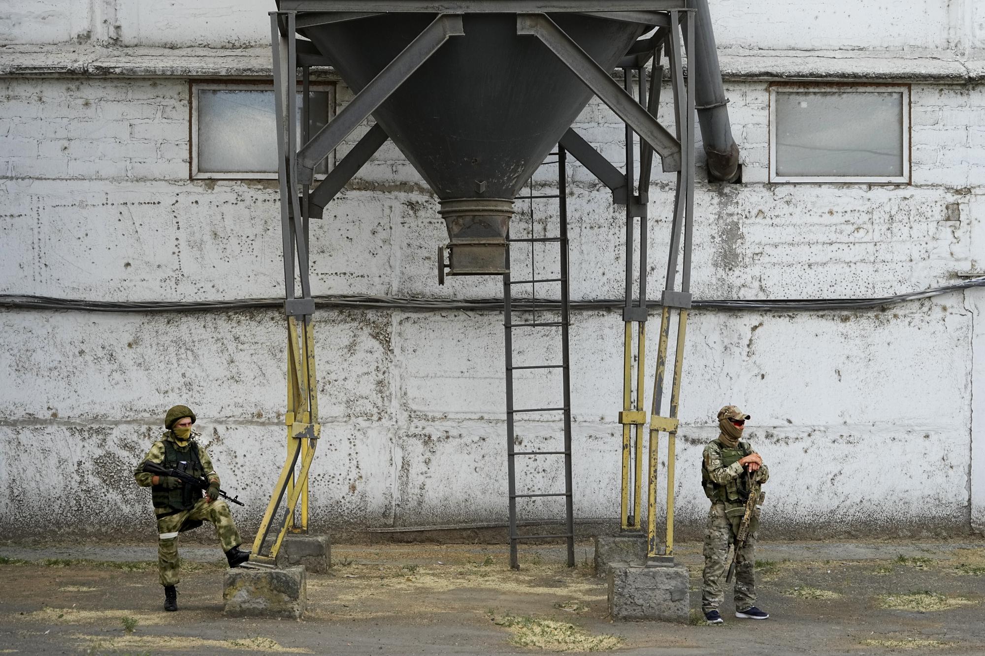 FILE - During a trip organized by the Russian Ministry of Defense, Russian soldiers stand guard as foreign journalists visit a grain elevator in Melitopol, southern Ukraine, Thursday, July 14, 2022. An investigation by The Associated Press shows a Russian-run smuggling operation has been transporting grain from occupied regions of Ukraine by train and truck to ports in Crimea, where it is shipped to buyers in the Middle East. (AP Photo, File)