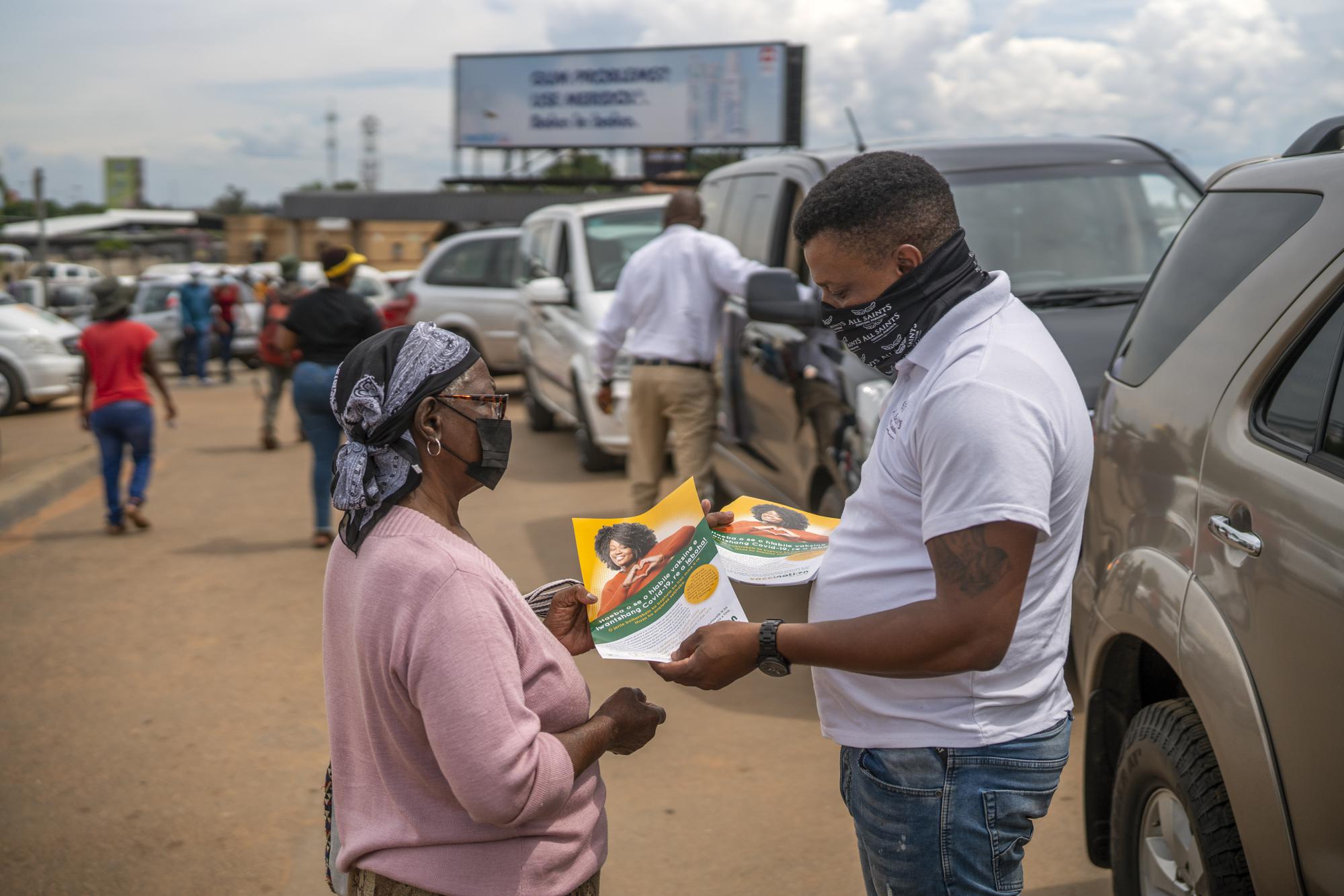 FILE - A Funeral Parlours Association member distributes a leaflet in Soweto, South Africa, Tuesday Dec. 7, 2021. Over 40 hearses took part in what was a COVID-19 vaccine awareness campaign, with the slogan: "We not in a hurry to see you!" (AP Photo/Jerome Delay, File)