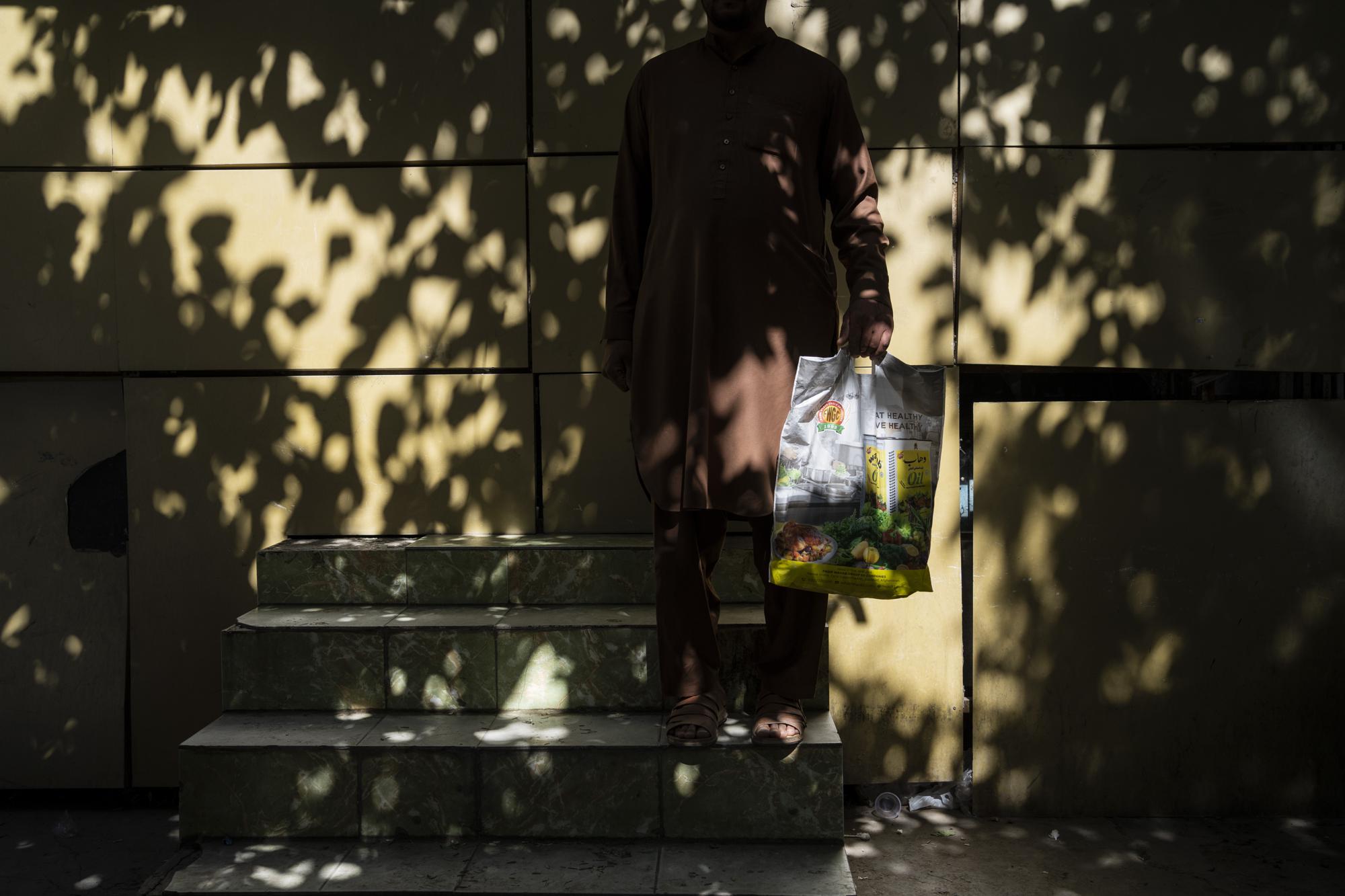 Kamal Khan poses with his luggage near the Islamabad embassy in Kabul, Afghanistan, Monday, Sept. 27, 2021. Khan wants to leave Afghanistan and go to Kuwait but has been waiting for a permit to cross into Pakistan. (AP Photo/Bernat Armangue)