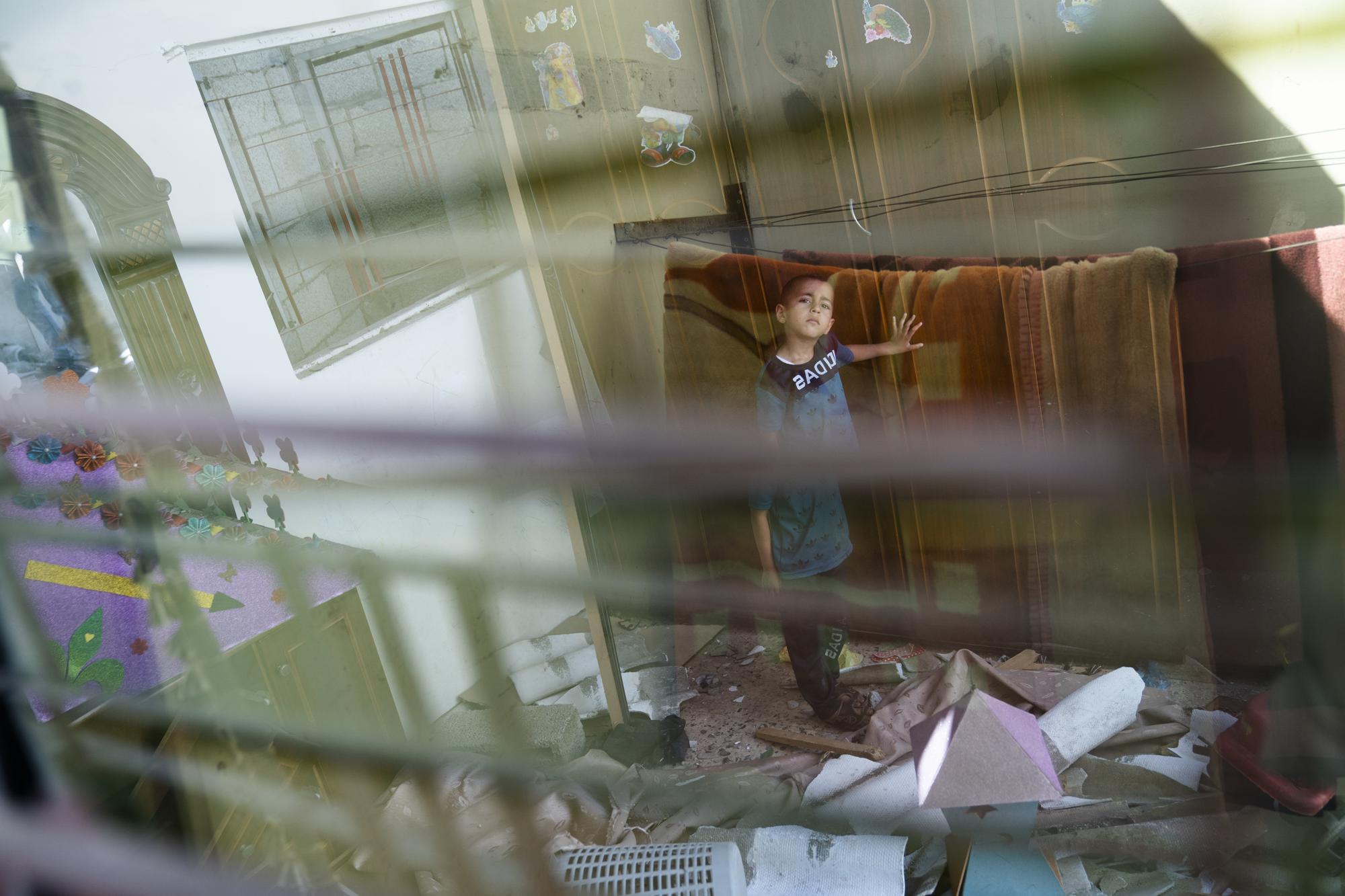 Anas Alhaj Ahmed, 4, stands for a portrait in his bedroom that was damaged when an airstrike destroyed a nearby building prior to a cease-fire that halted an 11-day war between Gaza's Hamas rulers and Israel, Thursday, May 27, 2021, in Maghazi, Gaza Strip. (AP Photo/John Minchillo)