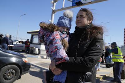 Una mujer lleva a su bebé en brazos tras huir de la guerra en la vecina Ucrania, en un paso fronterizo en Palanca, Moldavia, el sábado 19 de marzo de 2022. (AP Foto/Sergei Grits)