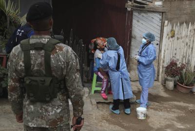 Escoltados por un soldado, dos médicos toman una muestra a Juana Bovadilla, de 79 años, durante una campaña de pruebas diagnósticas contra el COVID-19 en el barrio Villa María del Triunfo, el martes 12 de enero de 2021, en Lima, Perú. (AP Foto/Martín Mejía)
