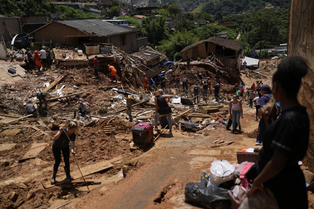 Los residentes ayudan a los trabajadores de rescate en el segundo día de esfuerzos para encontrar sobrevivientes y víctimas después de los deslizamientos de tierra mortales en Petrópolis, Brasil, el jueves 17 de febrero de 2022. , no estaba claro cuántos cuerpos quedaron atrapados en el lodo.  (Foto AP/Silvia Izquierdo)