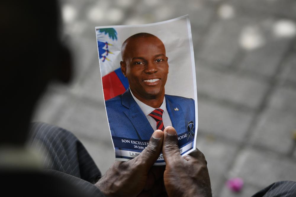 FILE - A person holds a photo of late Haitian President Jovenel Moise during his memorial ceremony at the National Pantheon Museum in Port-au-Prince, Haiti, Tuesday, July 20, 2021. Authorities in the Dominican Republic said Monday, Jan. 10, 2022, that they have arrested a key suspect in the killing of President Moise with help from the U.S. (AP Photo/Matias Delacroix, File)