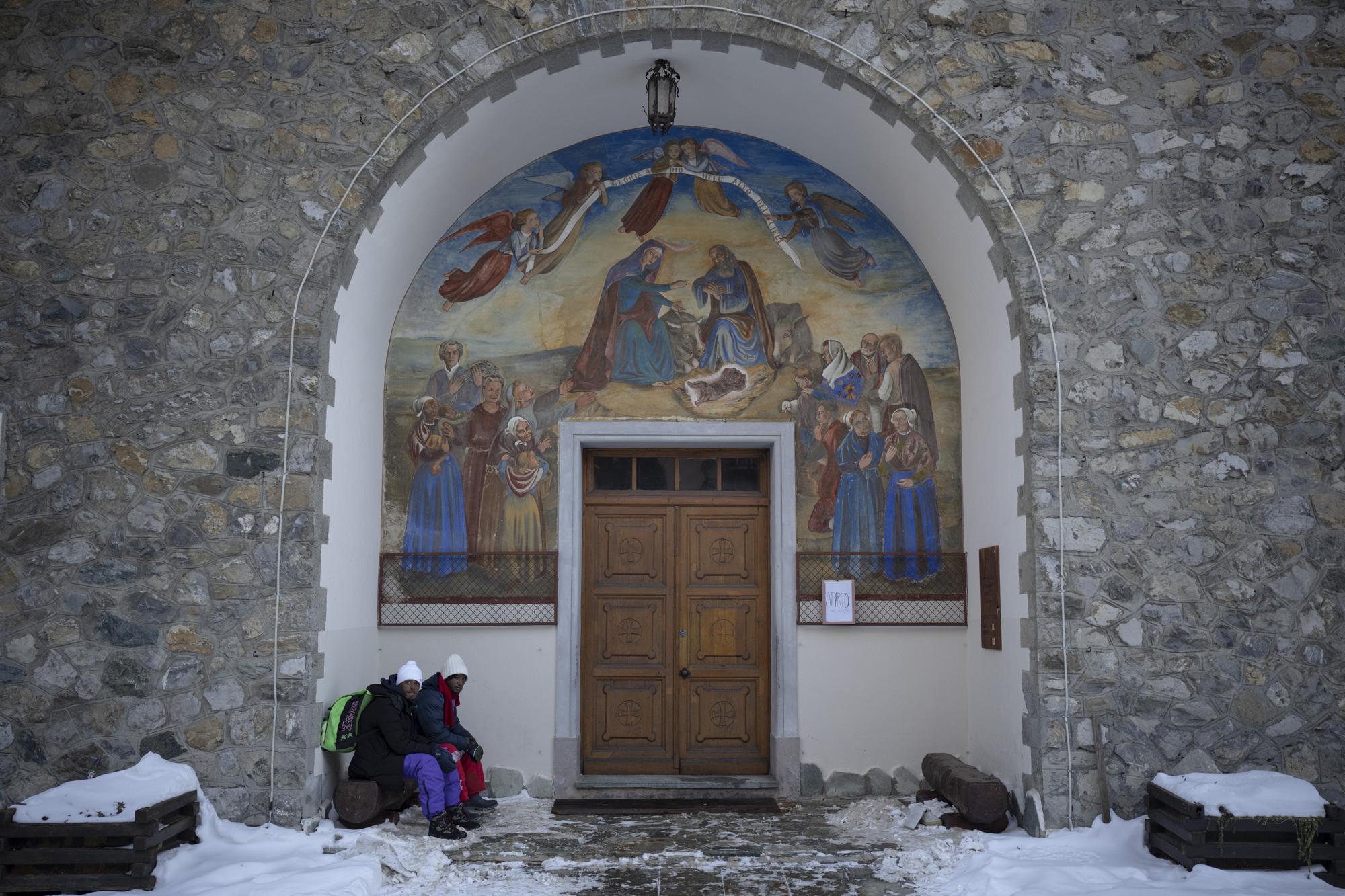 Ethiopian migrants take shelter under a church entrance in the Italian border town of Claviere before attempting to cross into the French Alps, Monday, Dec. 13, 2021. (AP Photo/Daniel Cole)
