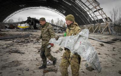 Zapadores ucranianos cargan un dron militar ruso teniendo como fondo el Antonov An-225, el avión de carga más grande del mundo, destruido por las tropas rusas durante los combates recientes, en el aeropuerto Antonov de Hostomel, en las afueras de Kiev, Ucrania, el lunes 18 de abril de 2022. (AP Foto/Efrem Lukatsky)