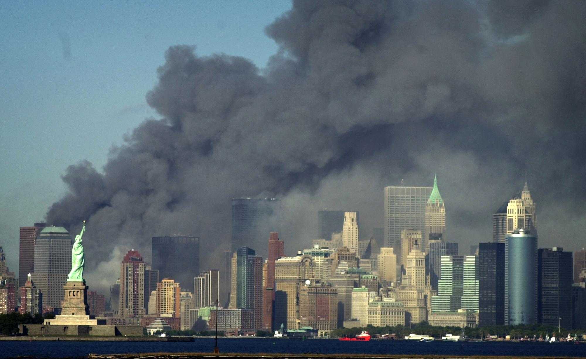 Thick smoke billows into the sky from the area behind the Statue of Liberty, lower left, where the World Trade Center was, on Tuesday, Sept. 11, 2001. (AP Photo/Daniel Hulshizer)