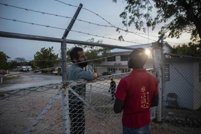 Un gerente en las instalaciones de Christian Aid Ministries, a la izquierda, habla el domingo 21 de noviembre de 2021 con un trabajador en la puerta del centro ubicado en Titanyen, al norte de Puerto Príncipe, Haití.  (AP Foto/Odelyn Joseph)