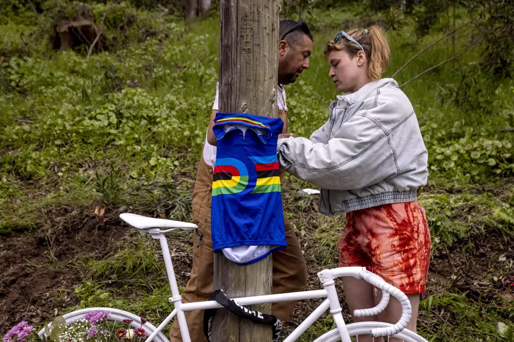 Sydney Parcell, right, and Wagner Sousa places a track cycling world champion jersey at a memorial, Thursday, April 6, 2023, in San Francisco, near where friend Ethan Boyes was fatally struck by a vehicle earlier in the week. (Stephen Lam/San Francisco Chronicle via AP)