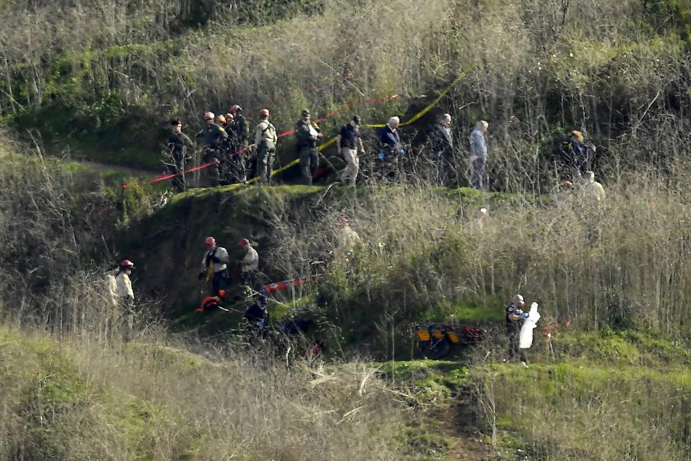 FILE - In this Jan. 27, 2020, file photo, investigators work the scene of a helicopter crash that killed former NBA basketball player Kobe Bryant in Calabasas, Calif. Los Angeles County is seeking to compel psychiatric evaluations for Kobe Bryant's widow and others to determine if they truly suffered emotional distress after first responders took and shared graphic photos from the site of the helicopter crash that killed the basketball star, his teenage daughter and seven others in 2020, court documents say. Vanessa Bryant, whose federal lawsuit against Los Angeles County alleges invasion of privacy, has claimed in court papers that she has suffered "severe emotional distress" that has compounded the trauma of losing her husband and 13-year-old daughter, Gianna. (AP Photo/Mark J. Terrill, File)