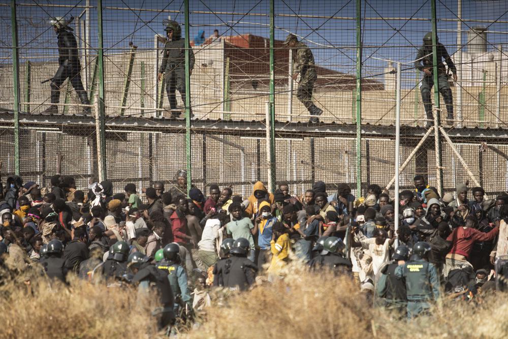 Riot police officers cordon off the area after migrants arrive on Spanish soil and crossing the fences separating the Spanish enclave of Melilla from Morocco in Melilla, Spain, Friday, June 24, 2022. Dozens of migrants stormed the border crossing between Morocco and the Spanish enclave city of Melilla on Friday in what is the first such incursion since Spain and Morocco mended diplomatic relations last month. (AP Photo/Javier Bernardo)