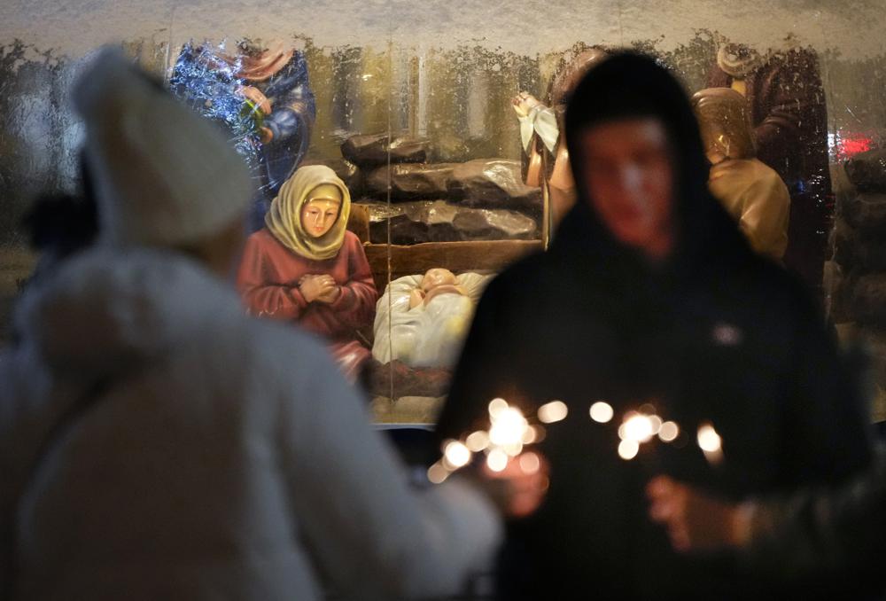 People burn sparklers near a Christmas crib next to a church during Orthodox Christmas celebrations in St. Petersburg, Russia, Friday, Jan. 7, 2022. Russian Orthodox believers celebrate Christmas in accordance to the Julian calendar on Jan. 7. (AP Photo/Dmitri Lovetsky)