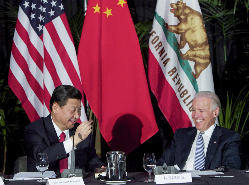 FILE - Xi Jinping, China's president and Communist Party chief, left, eats a Hawaiian macadamia chocolate gifted by Governor of Hawaii, Neil Abercrombie, not seen, during a governors meeting held inside the Walt Disney Concert Hall as Vice President Joe Biden, right, looks on in Los Angeles., Feb. 17, 2012. As President Joe Biden and Xi Jinping prepare to hold their first summit on Monday, Nov. 15, the increasingly fractured U.S.-China relationship has demonstrated that the ability to connect on a personal level has its limits. Biden nonetheless believes there is value in a face-to-face meeting, even a virtual one like the two leaders will hold Monday evening. (AP Photo/Damian Dovarganes, File)