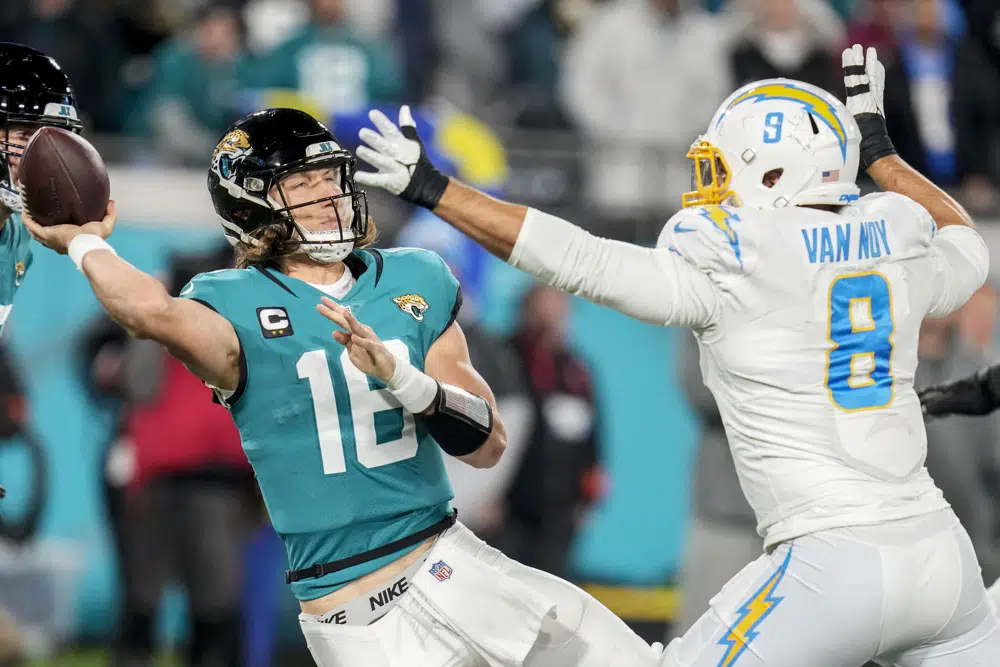 Jacksonville Jaguars quarterback Trevor Lawrence (16) tries to throw a pass under pressure by Los Angeles Chargers linebacker Kyle Van Noy (8) during the second half of an NFL wild-card football game, Saturday, Jan. 14, 2023, in Jacksonville, Fla. (AP Photo/John Raoux)