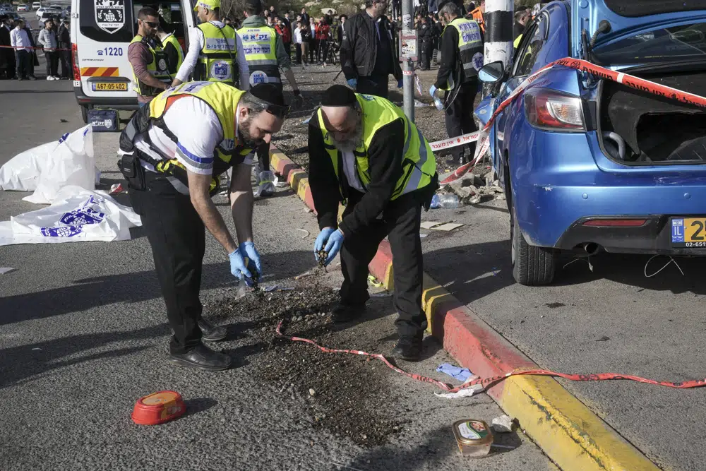 Members of Zaka Rescue and Recovery team work at the site of a car-ramming attack at a bus stop in Ramot, a Jewish settlement in east Jerusalem, Friday, Feb. 10, 2023. A driver plowed a car into a crowded bus stop in east Jerusalem on Friday, killing two people, including a six-year-old, and injuring five others before being shot and killed, Israeli police and medics said, the latest escalation as violence grips the contested capital. (AP Photo/Mahmoud Illean)