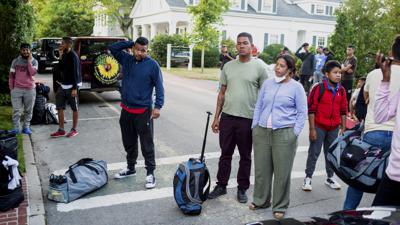 Migrantes enviados en avión de Texas a Massachusetts por el gobernador de Florida, Ron DeSantis, aguardan en la calle, el 14 de septiembre de 2022, en la localidad de Edgartown, en la isla Martha's Vineyard, Massachusetts. (Ray Ewing/Vineyard Gazette vía AP, archivo)