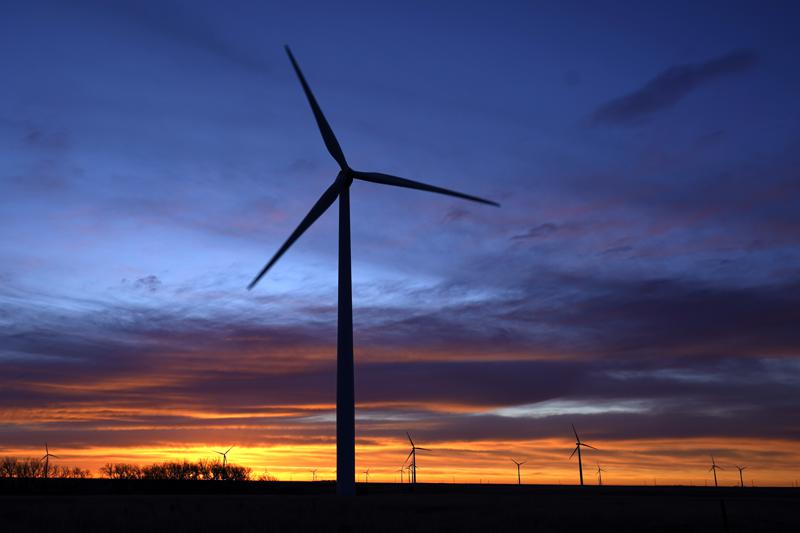 FILE - In this Jan. 13, 2021, file photo, wind turbines are silhouetted against the sky at dawn near Spearville, Kan. Evergy, Kansas' largest electric company expects to make its first big investments in solar energy over the next three years and increase wind generating capacity with the goal to produce no net carbon emissions as of 2045. (AP Photo/Charlie Riedel, File)