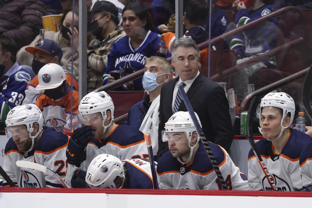 Edmonton Oilers head coach Dave Tippett, back, stands on the bench behind Leon Draisaitl, of Germany, from left to right, Warren Foegele, Ryan McLeod, Devin Shore and Jesse Puljujarvi, of Sweden, during the third period of an NHL hockey game against the Vancouver Canucks, Tuesday, Jan. 25, 2022 in Vancouver, British Columbia. (Darryl Dyck/The Canadian Press via AP)