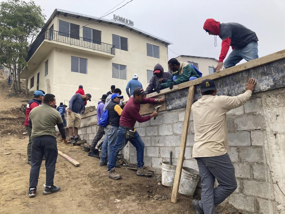 Voluntarios migrantes construyen un campo de fútbol en el Templo Embajadores de Jesús, el mayor albergue de la ciudad fronteriza mexicana de Tijuana, el 13 de octubre de 2022. El nuevo plan de EEUU que amplía las restricciones de asilo a los venezolanos supone un reto añadido para la ya desbordada red de albergues en México, que apenas puede hacer frente a la creciente llegada de extranjeros. Washington aceptará hasta 24.000 migrantes venezolanos que cumplan una serie de requisitos y devolverá a México a quienes entren de forma ilegal. (AP Foto/Elliot Spagat)