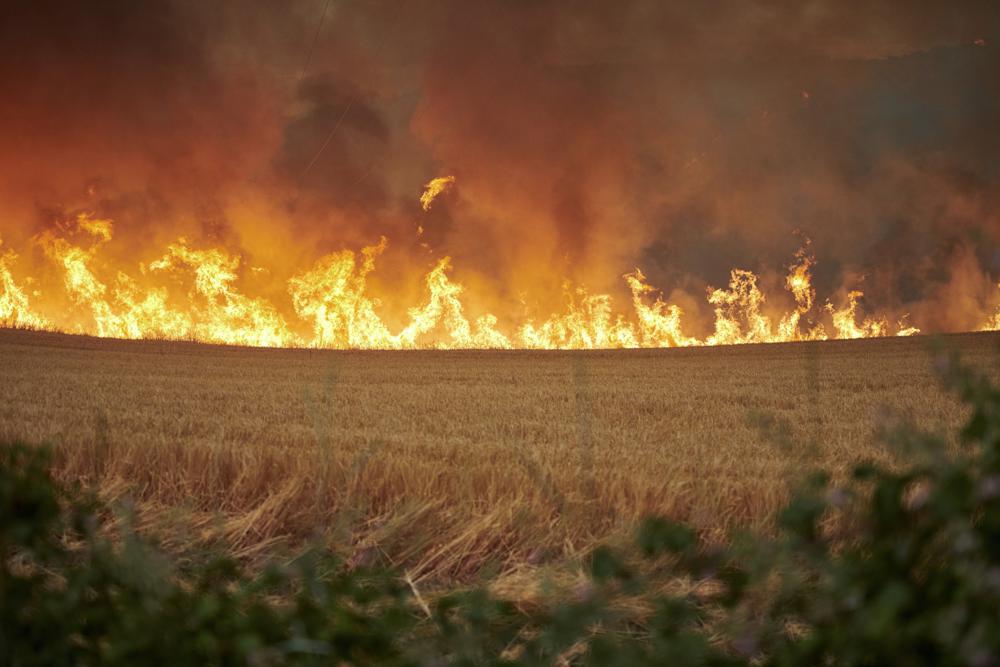 Flames rage in a field during a fire in Arraiza, northern Spain, Saturday, June 18, 2022. Firefighters in Spain are struggling to contain wildfires in several parts of the country suffering an unusual heat wave for this time of the year. (AP Photo/Sergio Martin)