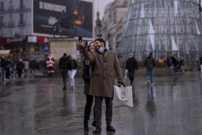 Una pareja se toma una foto en la Plaza del Sol en el centro de Madrid, el viernes 24 de diciembre de 2021. (AP Foto/Manu Fernández)