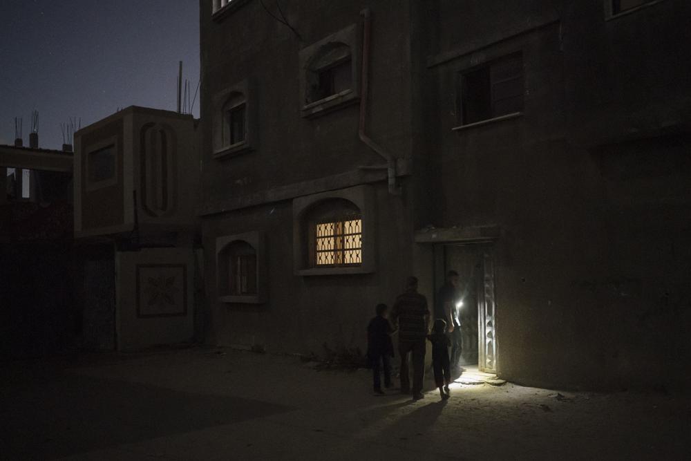 Zaki Nassir walks with his sons to an apartment he rented after their house was heavily damaged by airstrikes in Beit Hanoun, northern Gaza Strip, Wednesday, June 16, 2021. (AP Photo/Felipe Dana)