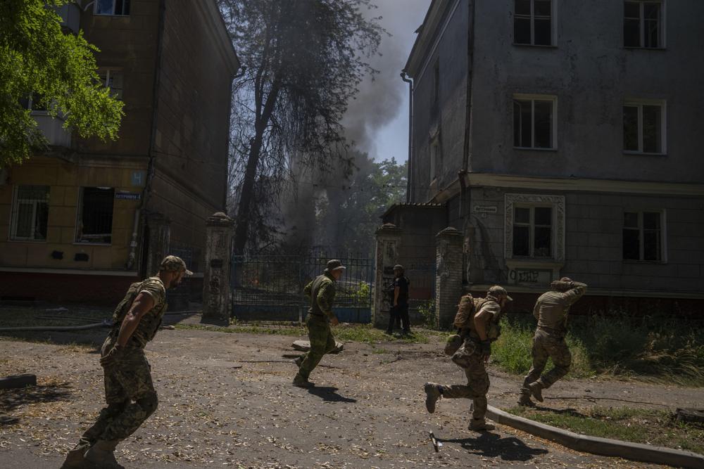 FILE - Ukrainian soldiers run after a missile strike hit a residential area, in Kramatorsk, Donetsk region, eastern Ukraine, Thursday, July 7, 2022. Injured residents sat dazed and covered in blood. A crater was now the centre of the courtyard. Last week, the governor of the Donetsk oblast Pavlo Kyrylenko urged the province's more than 350,000 remaining residents to flee to safer towns further West, saying that evacuating the region was necessary to save lives and allow the Ukrainian army to better defend towns against a Russian advance. Many refuse to leave the city. (AP Photo/Nariman El-Mofty, File)
