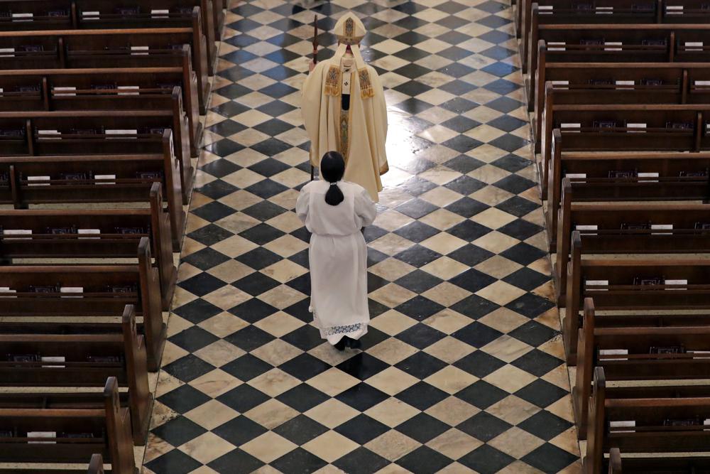 FILE - Archbishop Gregory Aymond conducts a procession to lead a live streamed Easter Mass in St. Louis Cathedral in New Orleans, Sunday, April 12, 2020. U.S. District Judge Greg Guidry donated tens of thousands of dollars to New Orleans’ Roman Catholic archdiocese and consistently ruled in favor of the church amid a contentious bankruptcy involving nearly 500 clergy sex abuse victims, The Associated Press found, an apparent conflict that could throw the case into disarray. (AP Photo/Gerald Herbert, File)