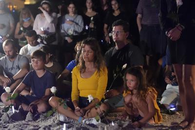 Varias personas participan en una vigilia el 28 de junio de 2021, en Surfside, Florida, en recuerdo de los fallecidos, heridos y desaparecidos tras el colapso de un edificio residencial. (AP Foto/Marta Lavandier)