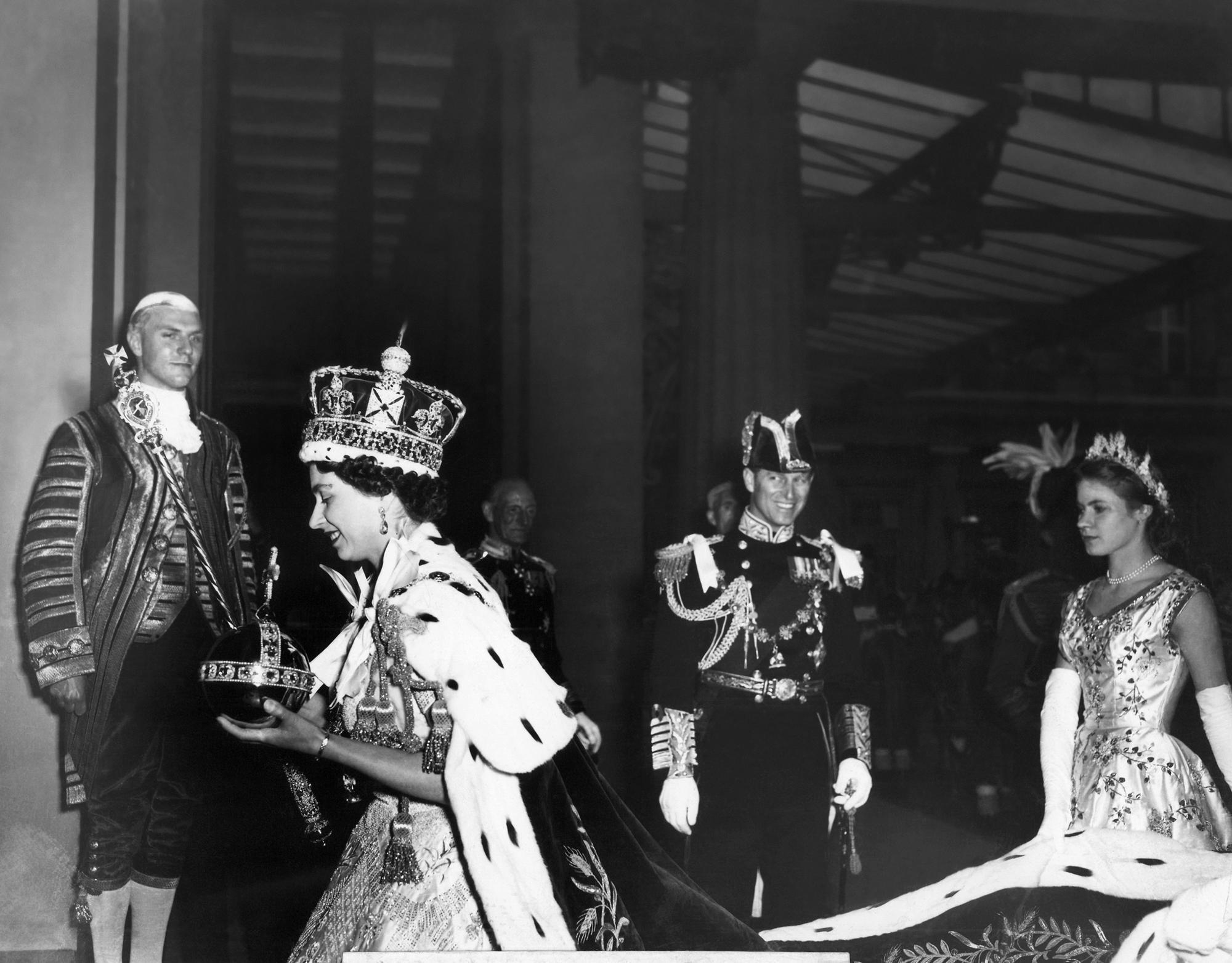 FILE - Britain's Queen Elizabeth II, carrying the orb and the scepter, enters Buckingham Palace after her Coronation ceremony in London's Westminster Abbey, June 2, 1953.Queen Elizabeth II, Britain’s longest-reigning monarch and a rock of stability across much of a turbulent century, has died. She was 96. Buckingham Palace made the announcement in a statement on Thursday Sept. 8, 2022. (AP Photo/Pool via AP, File)