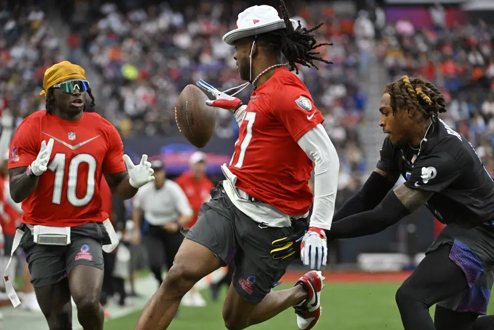 AFC wide receiver Davante Adams of the Las Vegas Raiders, center, pitches the ball back to AFC wide receiver Tyreek Hill (10) of the Miami Dolphins as NFC cornerback Jalen Ramsey of the Los Angles Rams defends during the flag football event at the NFL Pro Bowl, Sunday, Feb. 5, 2023, in Las Vegas. (AP Photo/David Becker)