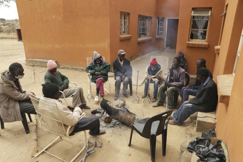 Elderly men gather around a fire at Melfort Old People's home on the outskirts of Harare, Zimbabwe, Sunday, July 25, 2021. The economic ravages of COVID-19 are forcing some families in Zimbabwe to abandon the age old tradition of taking care of the elderly. Zimbabwe's care homes have experienced a 60% increase in admissions since the outbreak of the pandemic in March last year. (AP Photo/Tsvangirayi Mukwazhi)