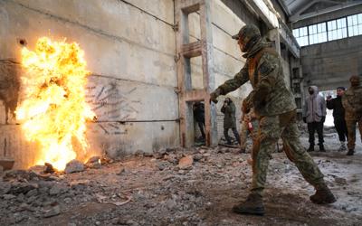 Un residente arroja una bomba molotov contra un muro durante una campaña ucraniana de entrenamiento militar, el domingo 6 de febrero de 2022, en las cercanías de Kiev, Ucrania. (AP Foto/Efrem Lukatsky)