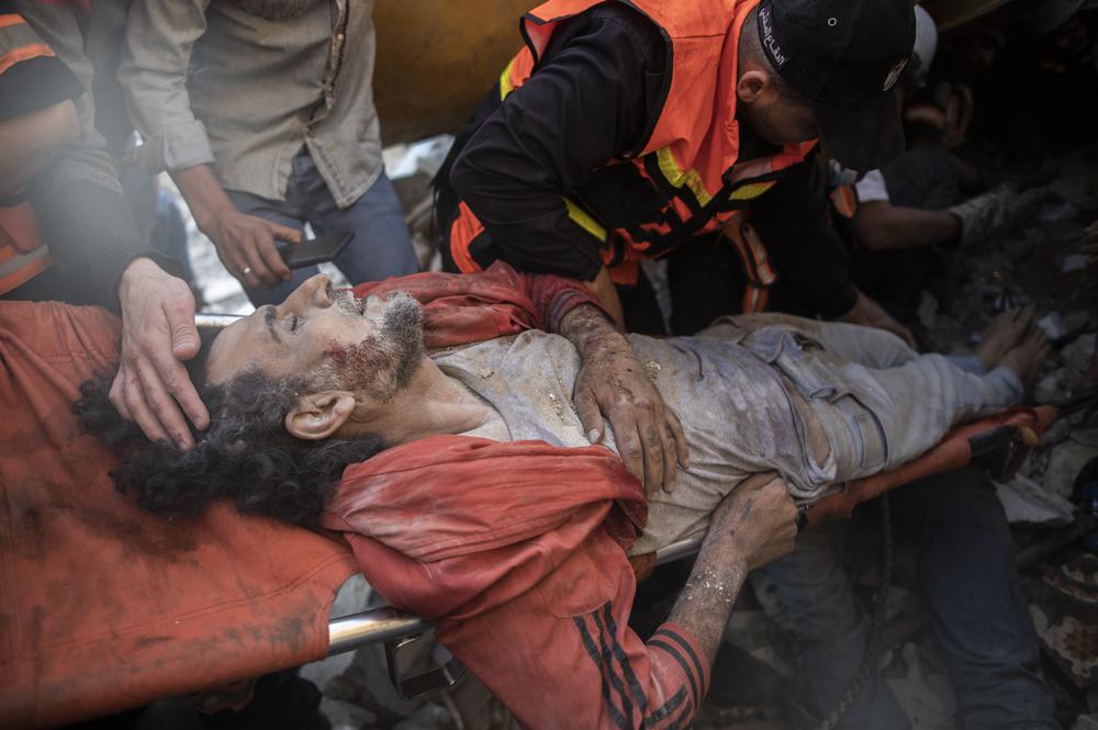 File - In this Sunday, May 16, 2021 file photo, Palestinian rescuers pull a survivor from under the rubble of one of al-Kawlak destroyed residential buildings following deadly Israeli airstrikes in Gaza City. The single deadliest bombing raid of Israel's fourth war with Hamas collapsed two apartment buildings and killed 22 members of the extended al-Kawlak family, including a 6-month-old boy and his 89-year-old great-grandfather. (AP Photo/Khalil Hamra, File)