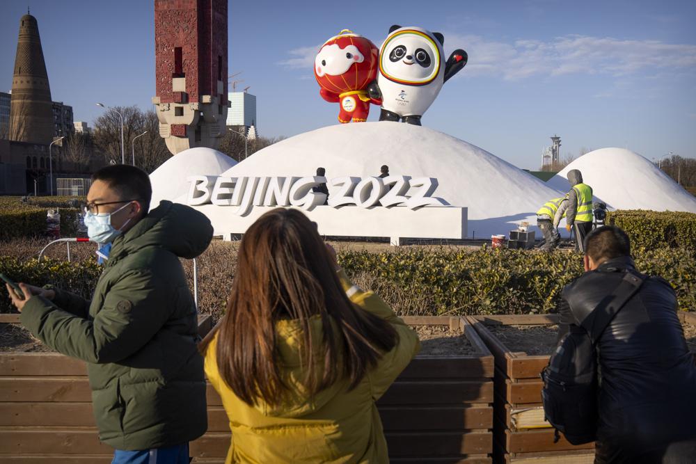 People wearing face masks to help protect against the coronavirus look at a display of the Winter Paralympic mascot Shuey Rhon Rhon, left, and Winter Olympic mascot Bing Dwen Dwen near the Olympic Green in Beijing, Wednesday, Jan. 12, 2022. Just weeks before hosting the Beijing Winter Olympics, China is battling multiple coronavirus outbreaks in half a dozen cities, with the one closest to the capital driven by the highly transmissible omicron variant. (AP Photo/Mark Schiefelbein)