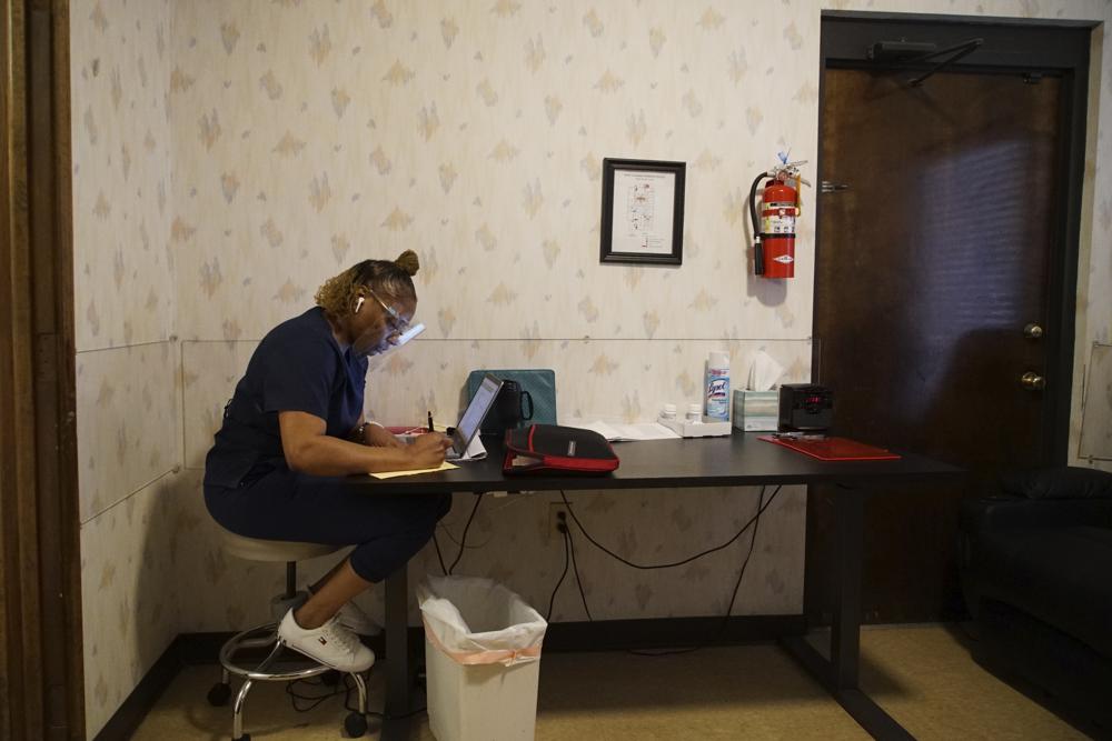 Ramona, quien pidió que no se usara su apellido, trabaja en la sala de recuperación del Centro de Mujeres de West Alabama en Tuscaloosa, Alabama, el martes 15 de marzo de 2022. El estuche verde contra la pared contiene su Biblia, que lee todos los días durante su hora de almuerzo.  (Foto AP/Allen G. Breed)