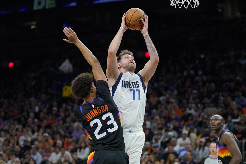 Luka Doncic (77), de los Mavericks de Dallas, ataca la canasta sobre Cameron Johnson (23), de los Suns de Phoenix, durante la segunda mitad del Juego 7 de las semifinales de la Conferencia Oeste, en los playoffs de la NBA, el domingo 15 de mayo de 2022, en Phoenix. Los Mavericks derrotaron a los Suns 123-90. (AP Foto/Matt York)