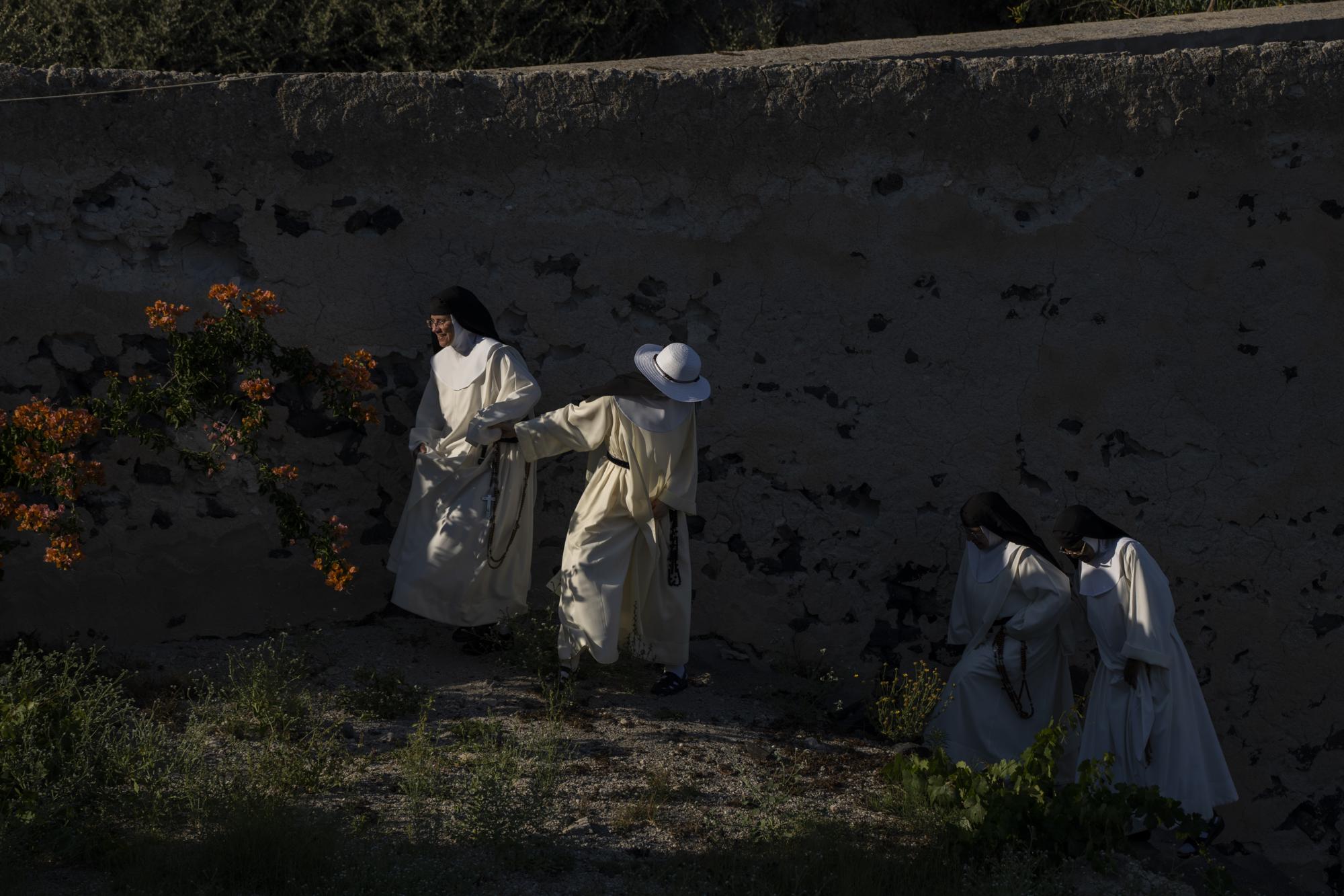 De izquierda a derecha, las monjas de clausura Sor María Flor, Sor María de la Trinidad, Sor María de Jesús y Sor María Teresa caminan en el jardín del Monasterio Católico de Santa Catalina en la isla griega de Santorini el miércoles 15 de junio de 2022 Cuando no están rezando en la iglesia o practicando música sacra e himnos, las monjas cuidan un jardín donde cultivan frutas y verduras.  (Foto AP/Petros Giannakouris)