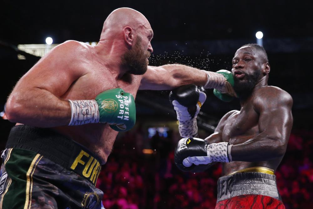 Tyson Fury, of England, hits Deontay Wilder in a heavyweight championship boxing match Saturday, Oct. 9, 2021, in Las Vegas. (AP Photo/Chase Stevens)