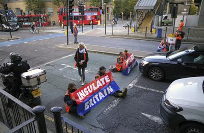 Manifestantes del grupo Aislan Gran Bretaña bloquean una calle cerca del centro financiero Canary Wharf en el este de Londres, el lunes 25 de octubre de 2021. (Victoria Jones/PA vía AP)