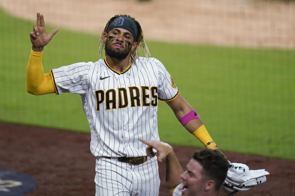 El campocorto de los Padres de San Diego, Fernando Tatis Jr., hace un gesto junto a un compañero de equipo después de un jonrón de Wil Myers durante la séptima entrada del Juego 2 de la serie de comodines de la Liga Nacional.