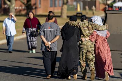 ARCHIVO - En imagen de archivo del 27 de septiembre de 2021, una mujer integrante de las fuerzas militares abraza a dos refugiadas afganas después de conversar con el secretario de Defensa Lloyd Austin en un campamento para refugiados en la base militar conjunta McGuire Dix Lakehurst, en Nueva Jersey. (AP Foto/Andrew Harnik, archivo)
